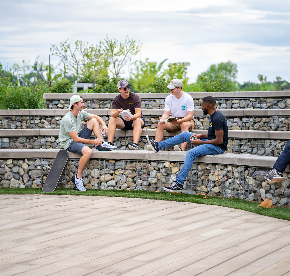 A group of Rowan students sitting on gabion wall steps.