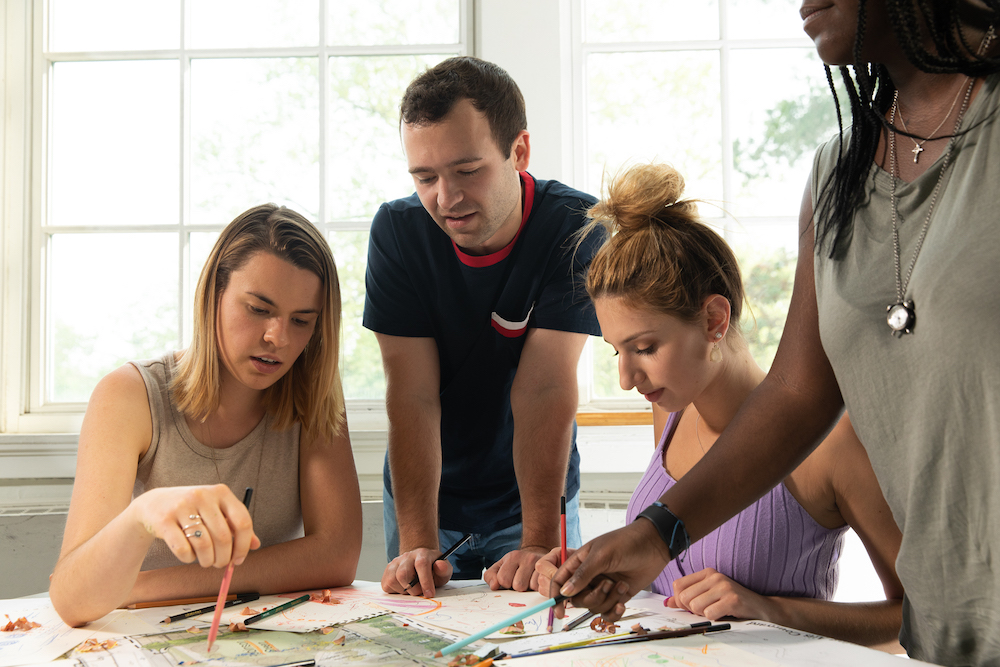 Four students in a classroom coloring an art project