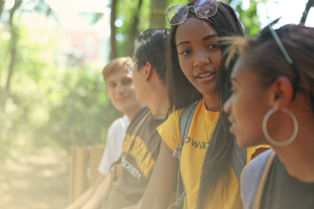 Four students sitting in a bench, with one girl facing the camera.