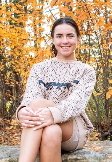 Rowan University student Trinity sits demurely while smiling.