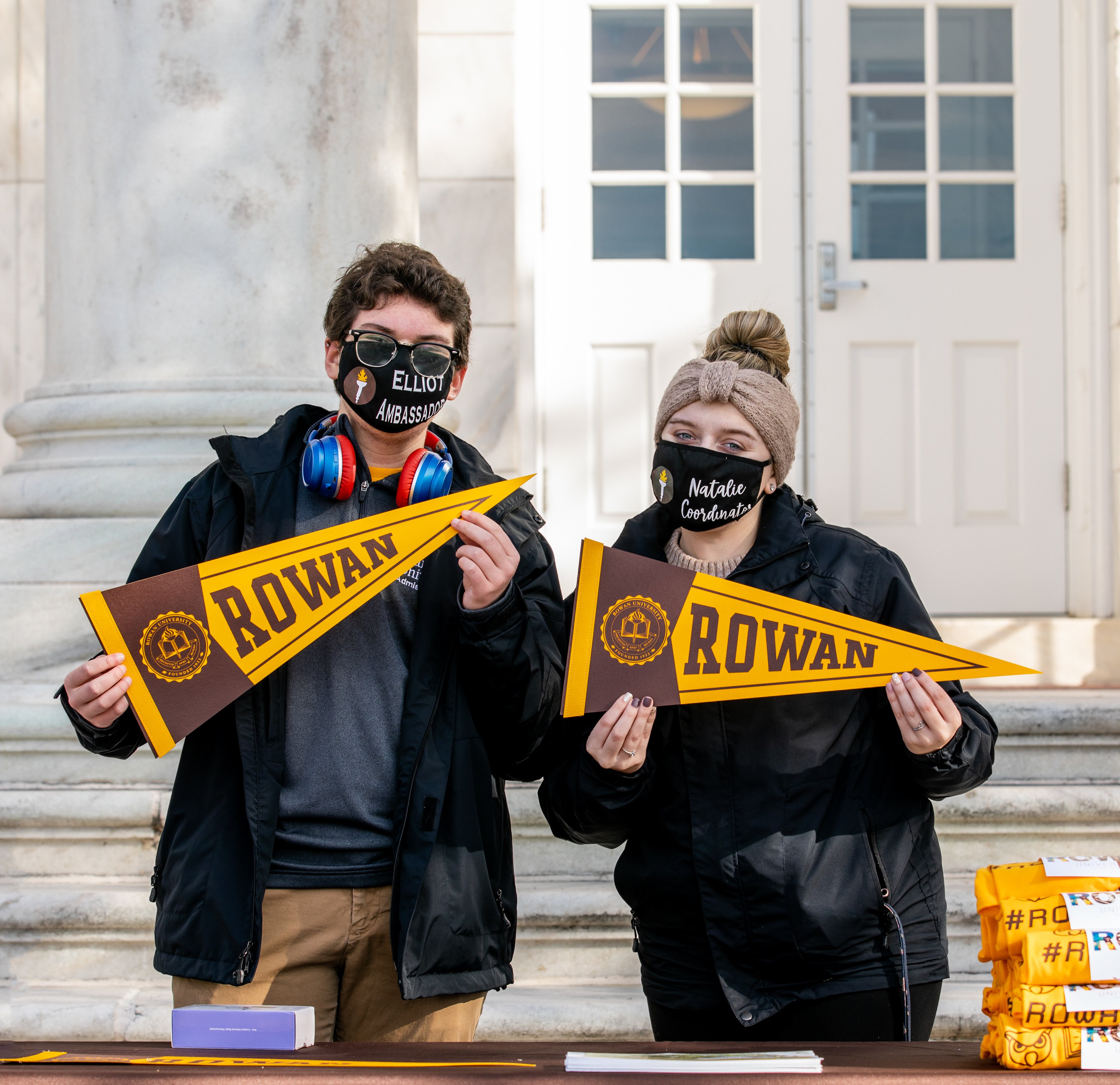 Two students standing holding Rowan pennants.